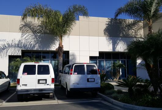 White industrial building at 5600 Everglades with 3 white vans parked in front
