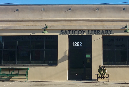 Front of building of Saticoy Library showing the front door and sculpture of children reading on a bench