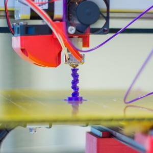 Photo of a 3D pinter printing something purple.