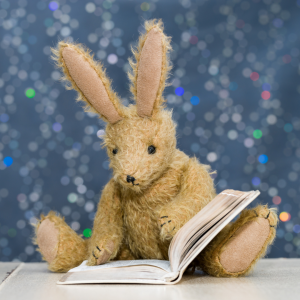 Photo of a plush bunny reading a book.