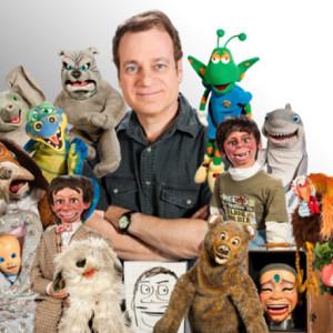 Joe Gandelman surrounded by many puppets